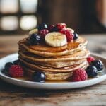A stack of whole wheat pancakes with fresh berries and honey.